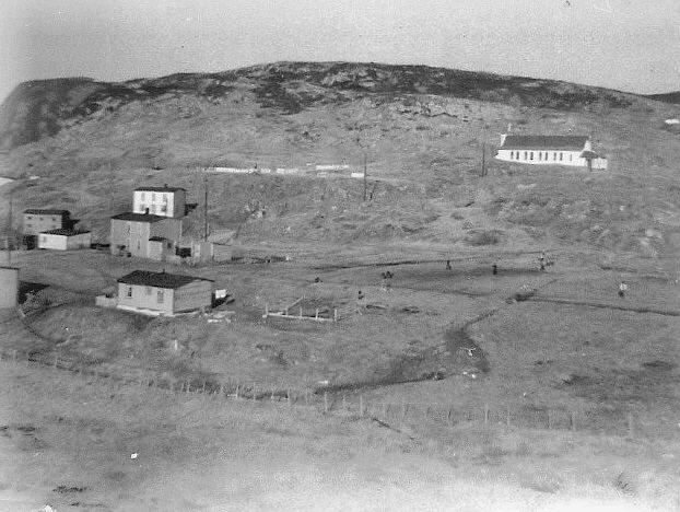 13 Across Tom Best's meadow with ballgame in progress. In the foreground: Clem Best's house; behind that is Lar Pitcher's house (built by Tom Best); behind that is Angus Pitcher's house (occupied by Joe Connors and Lambert Connors previously).&amp;nbsp; To the right is Tom Best's meadow (looks like a game of rounders being played!).&amp;nbsp; The wire fence separates the Priest's meadow and that fence was to keep the sheep out of the Priest's Meadow and to keep Monsignor Fyme's goats from getting out, which didn't always work...(He had yokes around the necks of the bigger ones to keep them from jumping the fence, but once in a while one escaped).